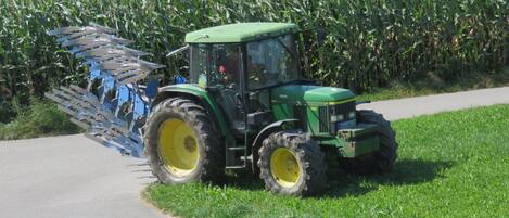 Un tracteur vert avec un accessoire bleu, dans un champ.
