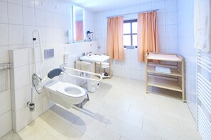 A modern bathroom with a toilet, bidet, and sink, equipped with a hand dryer and a towel rack. - Apartment Oberstadel 52 sqm for 1-4 persons barrier-free (Altötting)