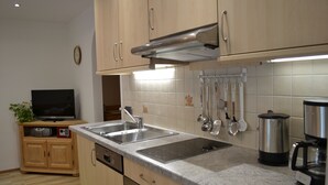 A kitchen with wooden cabinets, a stainless steel sink, a built-in oven, and a coffee maker.