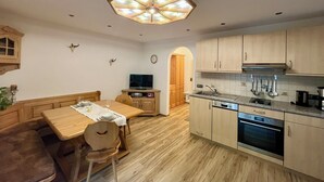 A compact kitchen with wooden cabinets, a built-in oven, and a dining area with a wooden table and chairs.