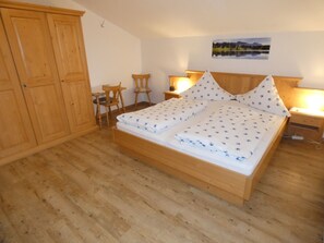 A bedroom with a wooden bed, two bedside tables, a chair, and a wardrobe. - holiday flat "Traunstein" (80 qm), balcony, kitchen, 3 bedrooms, 1 livingroom, max. 6 persons (Ruhpolding)