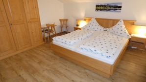 A bedroom with a wooden bed, two bedside tables with lamps, a chair, a desk, and a wardrobe. - holiday flat "Traunstein" (80 qm), balcony, kitchen, 3 bedrooms, 1 livingroom, max. 6 persons (Ruhpolding)