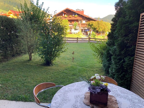 A table with a floral centerpiece and a chair, set against a backdrop of a building and a grassy area. - FEWO am Hauchen, 85 qm mit Tiefgarage und Terrasse (Reit im Winkl)
