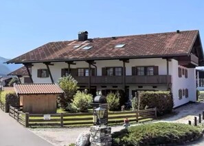 A traditional chalet-style building with a sloped roof, multiple windows, and a small attached structure. - FEWO am Hauchen, 85 qm mit Tiefgarage und Terrasse (Reit im Winkl)