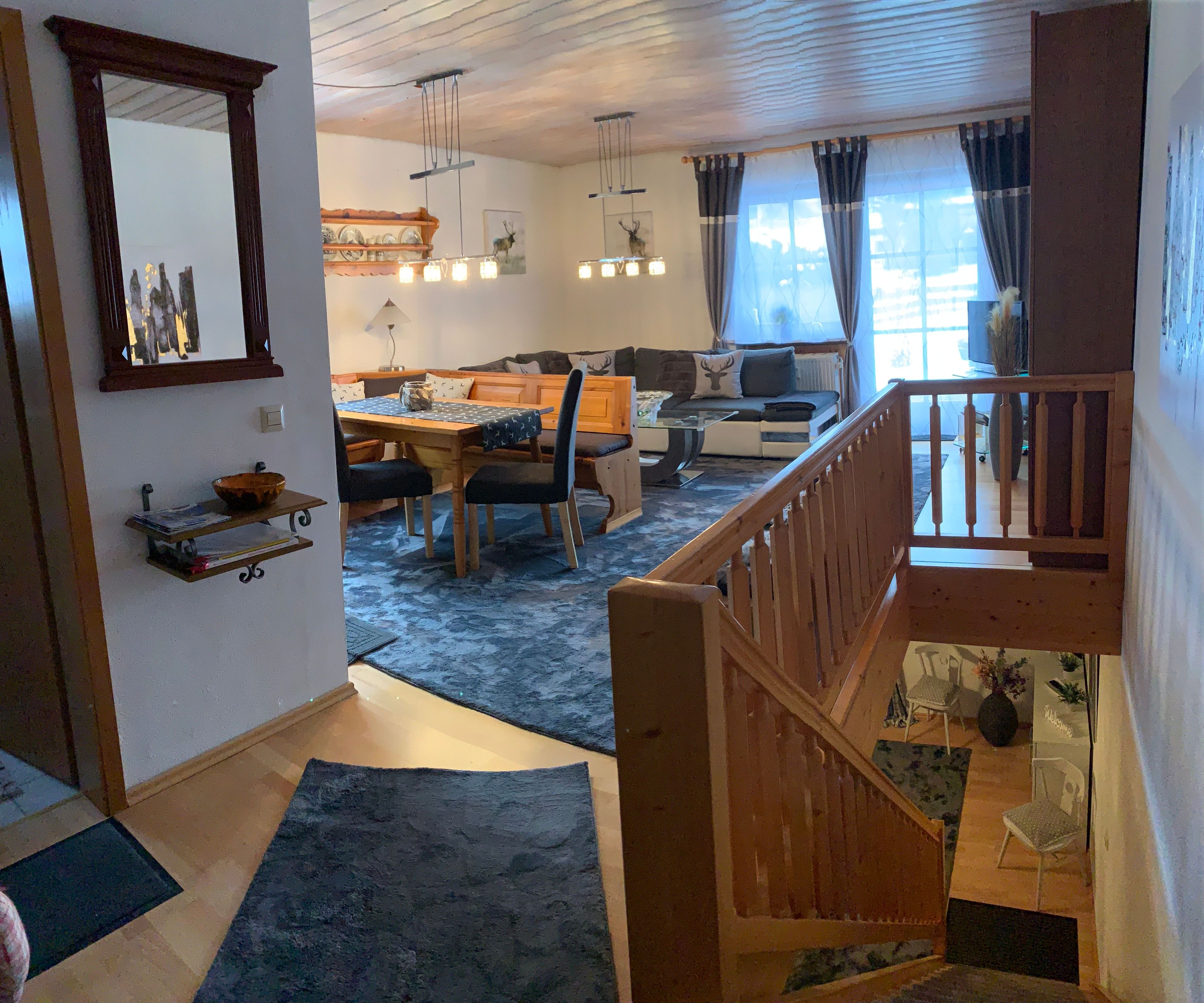 A spacious living area with a dining table, sofa, and a staircase leading to an upper level.