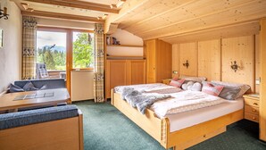 Une chambre confortable avec un lit en bois, un petit bureau et une vue sur l’extérieur.