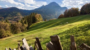 Un paysage montagneux avec un champ herbeux et une clôture en bois au premier plan.