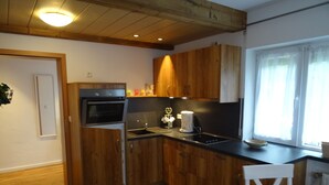 A compact kitchen with wooden cabinets, a built-in oven, and a coffee maker. - Vacation apartment Josefa, 2 persons, 1 bedroom, kitchenette, terrace, 55 sqm (Inzell)