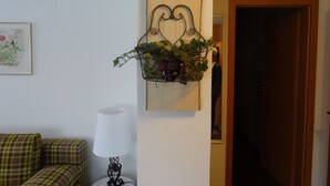 A living room with a plaid sofa, a lamp, and a wall-mounted plant holder with greenery. - Vacation apartment Josefa, 2 persons, 1 bedroom, kitchenette, terrace, 55 sqm (Inzell)