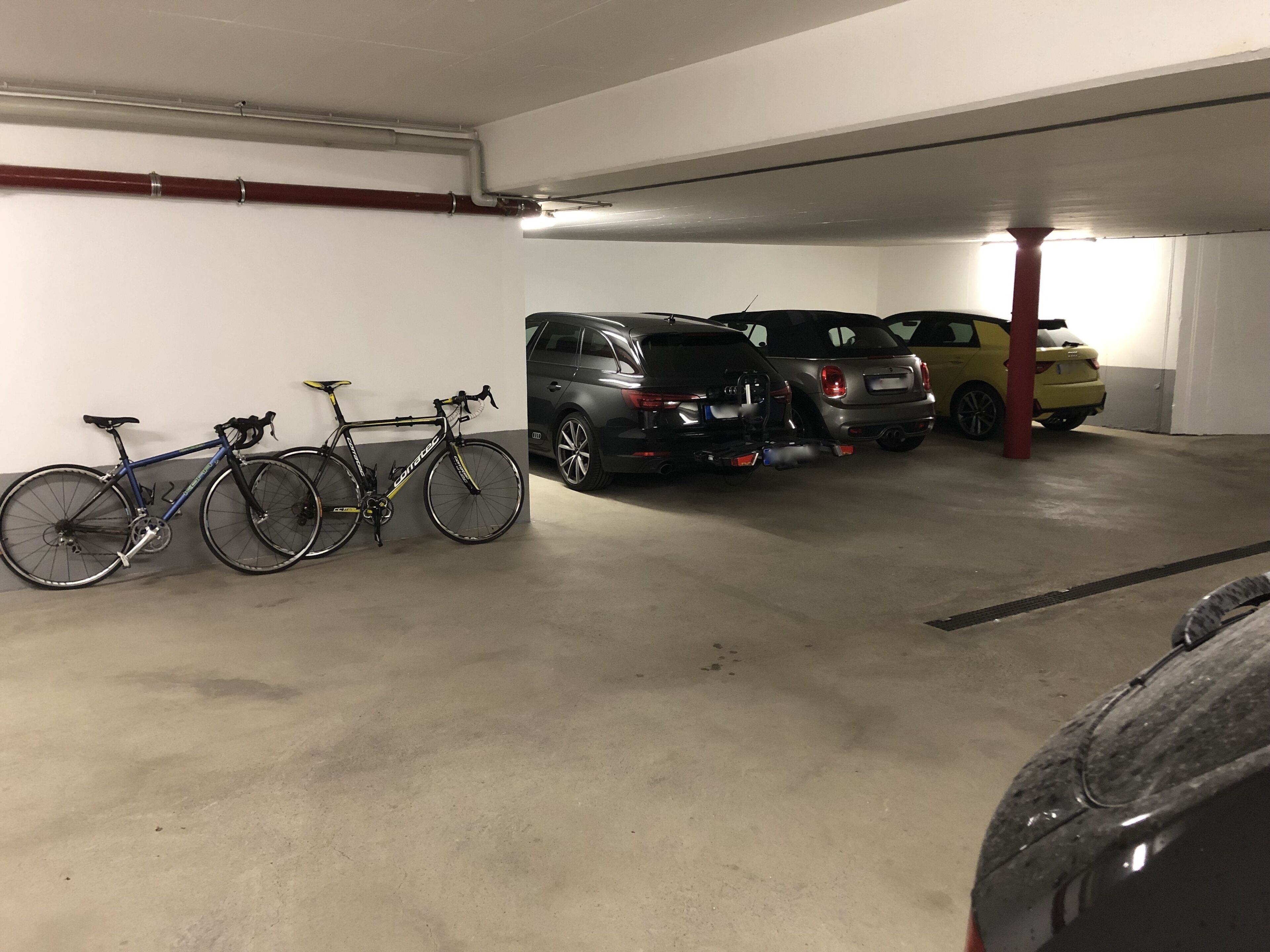 Un aparcamiento con varios coches y bicicletas.