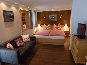 A bedroom with a bed, a sofa, a television, and a wardrobe.
