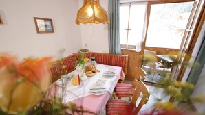 Un coin repas avec une table mise pour le petit-déjeuner, un banc et une vue sur l’extérieur.
