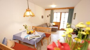 Un coin repas chaleureux avec une table en bois dressée pour deux personnes, un banc et un canapé.