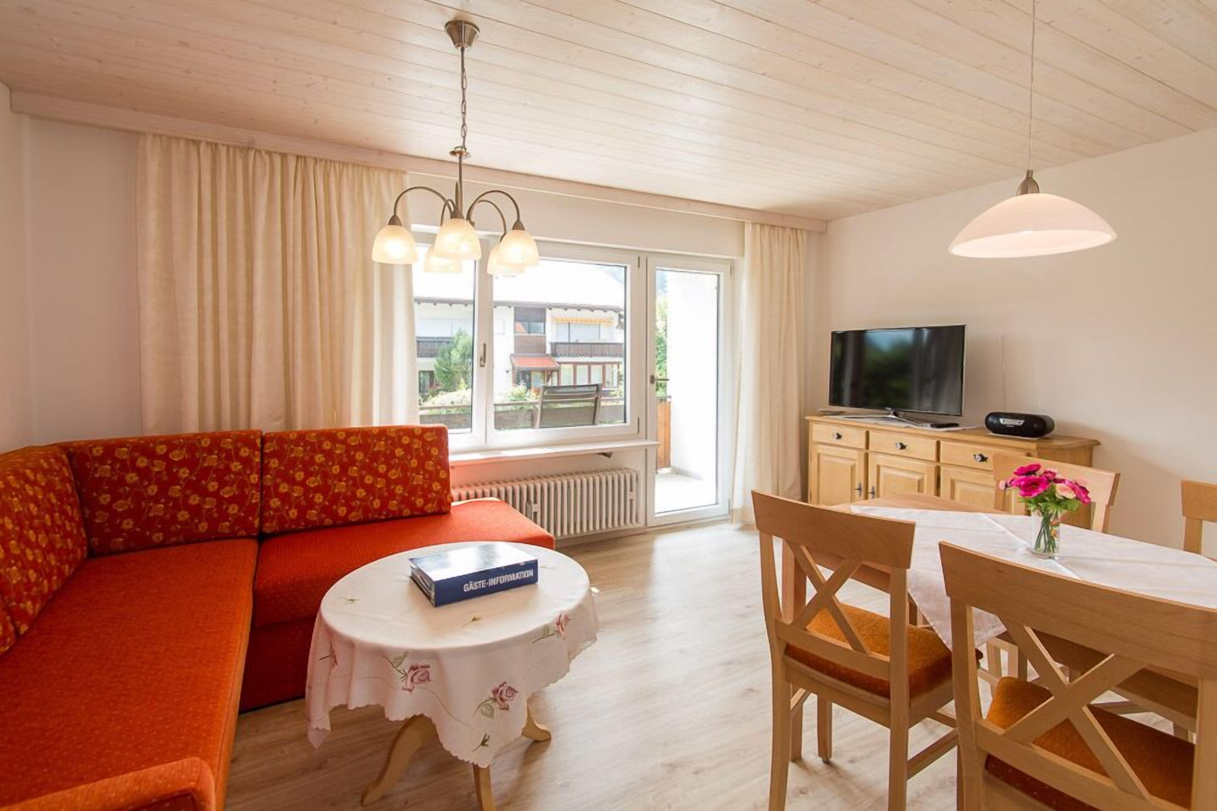 Ein gemütliches Wohnzimmer mit einer Couch, einem Esstisch und einem Fernseher.