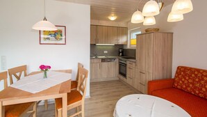 Una cucina compatta con mobili in legno, un tavolo da pranzo con sedie e un divano.