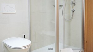 A modern bathroom with a glass-enclosed shower, a toilet, and a white sink. - Two-room apartment 5, approx. 40sqm with spacious balcony and mountain view (Reit im Winkl)