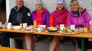 Four people seated at a table with breakfast items. - Ferienwohnung Nr. 3 Untersbergblick, 1 bis 2 Personen, 45 qm, 1 Schlafzimmer, Wohnraum mit Schlafcouch, Balkon (Schönau am Königssee)
