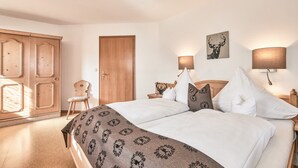 A bedroom with a bed, wooden wardrobe, and a door. - (5) Zwei-Raum-Ferienwohnung 50qm, Dusche/WC, Extra-Schlafraum, Küche, Balkon (Reit im Winkl)