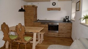 A compact kitchen with wooden cabinetry, a dining table with chairs, and a built-in oven.
