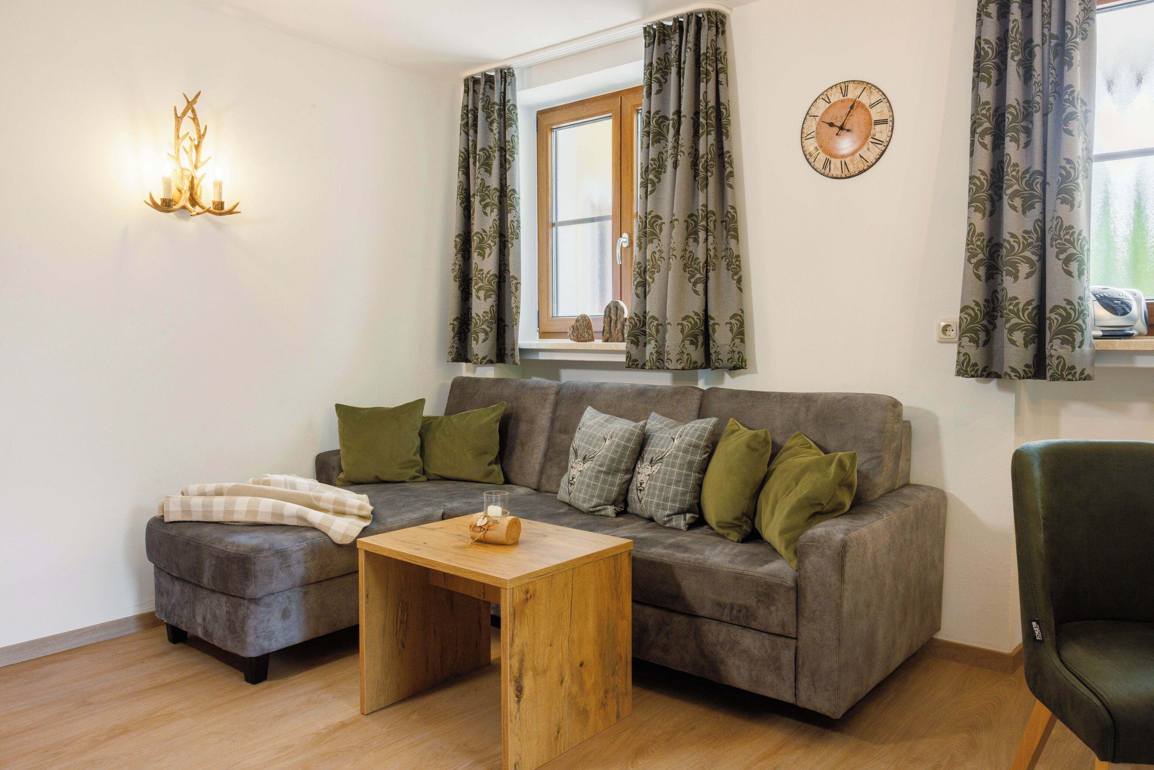 A living room with a grey sofa, a wooden coffee table, and a green armchair.