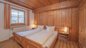 Un dormitorio con paneles de madera, dos camas, una ventana con cortinas y lámparas de noche.