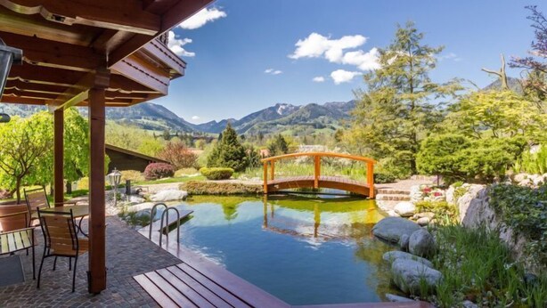 A wooden deck with a pool, a wooden bridge, and a mountain backdrop.