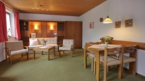 Una habitación acogedora con techo de madera, un sofá, una mesa de comedor con sillas y un mueble pequeño.