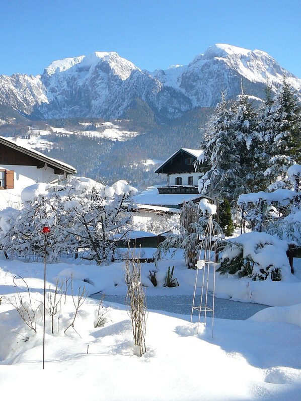 A snow-covered mountain landscape with a chalet-style building in the foreground.