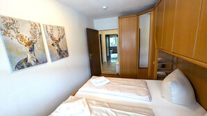 A bedroom with a bed, a wardrobe, and two wall-mounted paintings.