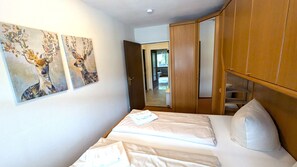 Une chambre à coucher comprenant un lit, une armoire et deux tableaux accrochés au mur.
