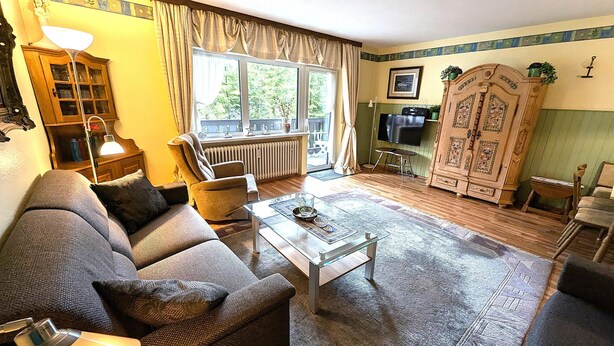 A living room with a sofa, armchair, coffee table, and a cabinet.