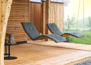 Un pontile in legno con due poltrone da relax e un tavolino con una candela.