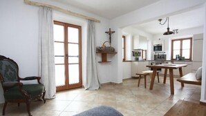 A spacious living area with a large window, a dining table, and a cozy armchair. - Vacation apartment Sophie, 70 sqm, first floor, 2 bedrooms (Schechen)
