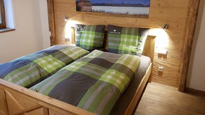 Una cama de madera con ropa de cama a cuadros y un cuadro de montañas en el cabecero.
