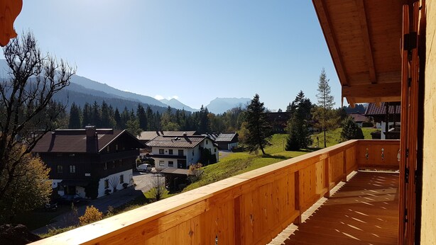 Un balcón de madera con vistas a un pueblo y montañas.