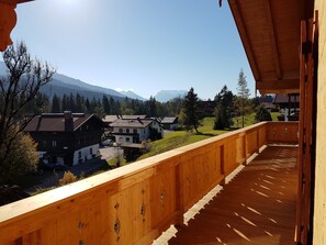 Un balcón de madera con vistas a un pueblo y montañas.