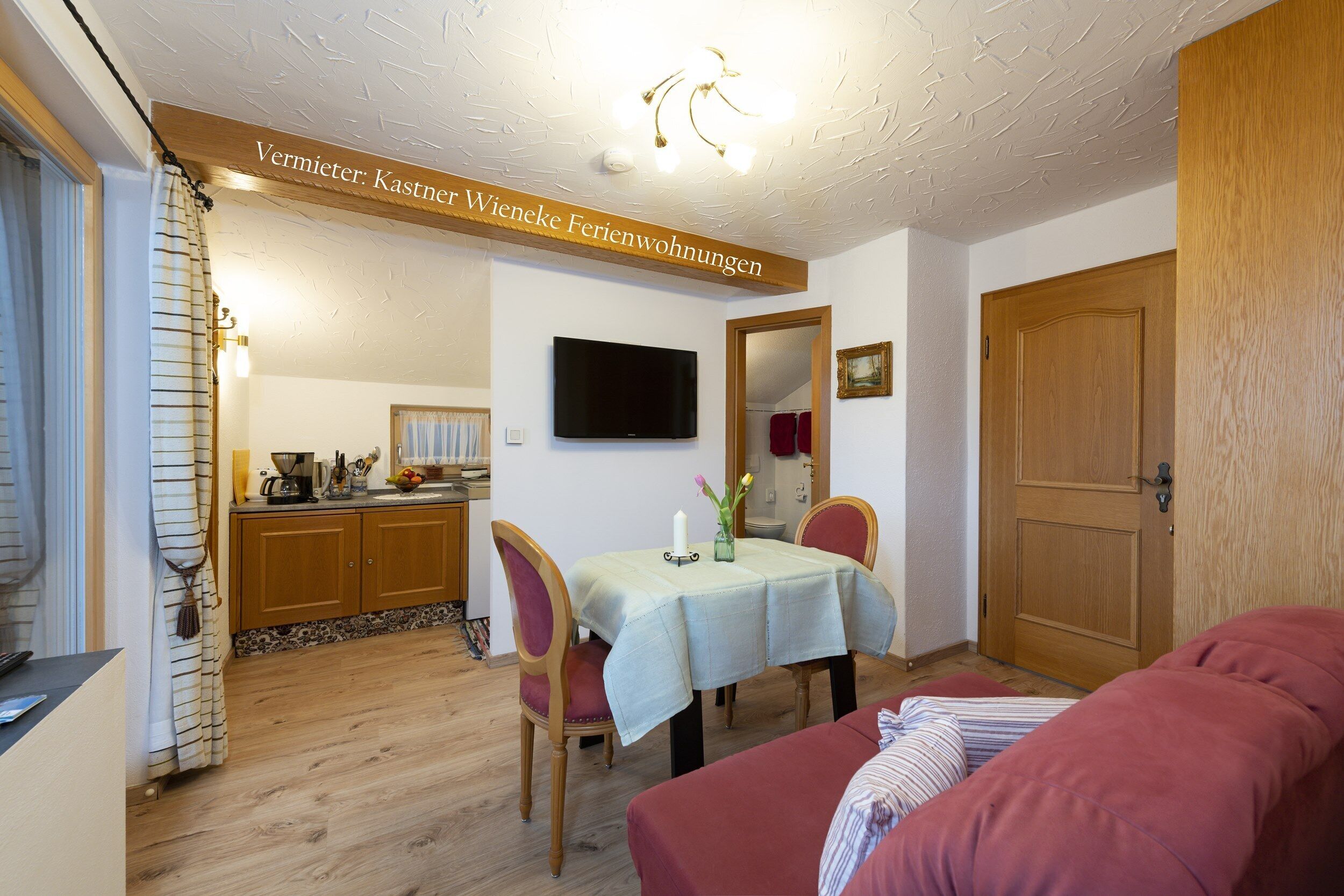 A cozy room with a dining table, chairs, a television, and a wooden door.