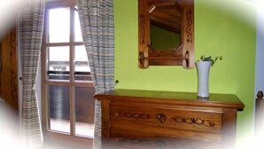 Una habitación con un aparador de madera, un espejo y una ventana con cortinas.