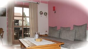 Una sala de estar con una mesa de centro de madera, un sofá gris y un ventanal corredizo que da a un espacio exterior.