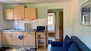 A compact kitchen with wooden cabinets, a microwave, and a coffee maker on the countertop. - (2) Zwei-Raum-Ferienwohnung 40qm, 1-4 Personen, Extra-Schalfzimmer, Wohnküche, große Balkonterrasse (Reit im Winkl)