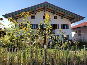 A two-story house with a red-tiled roof and green trim. - Edelweiss vacation apartment 64 m², 2 bedrooms, kitchen/living room, bathroom/WC, WLAN (Marquartstein)