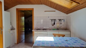 Cocina pequeña equipada con estufa, lavamanos y utensilios colgantes.