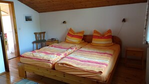 Una cama de madera con ropa de cama a rayas, una mesita de noche y un tocador.