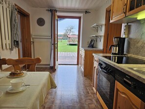 A kitchen with a stove, coffee maker, and a dining area with a table and chairs.