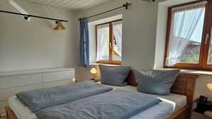 Un lit double avec une tête de lit en bois, une table de chevet avec une lampe et une fenêtre avec des rideaux.