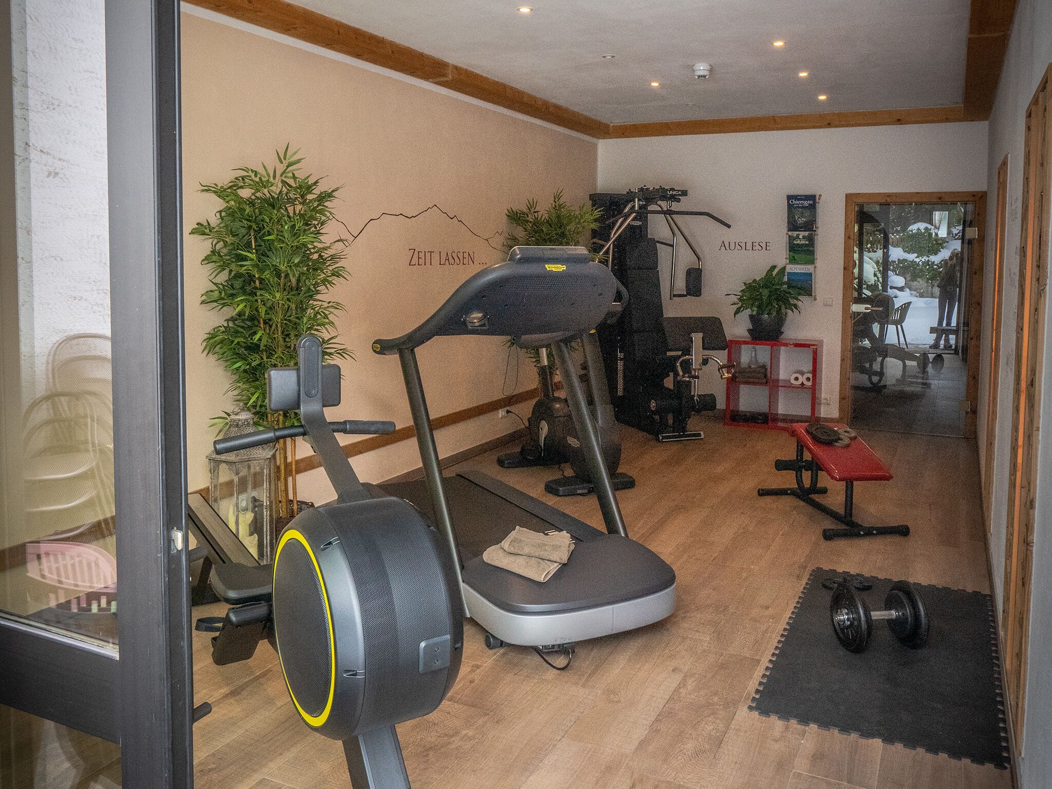 A gym with exercise equipment, a treadmill, a stationary bike, and a red bench.