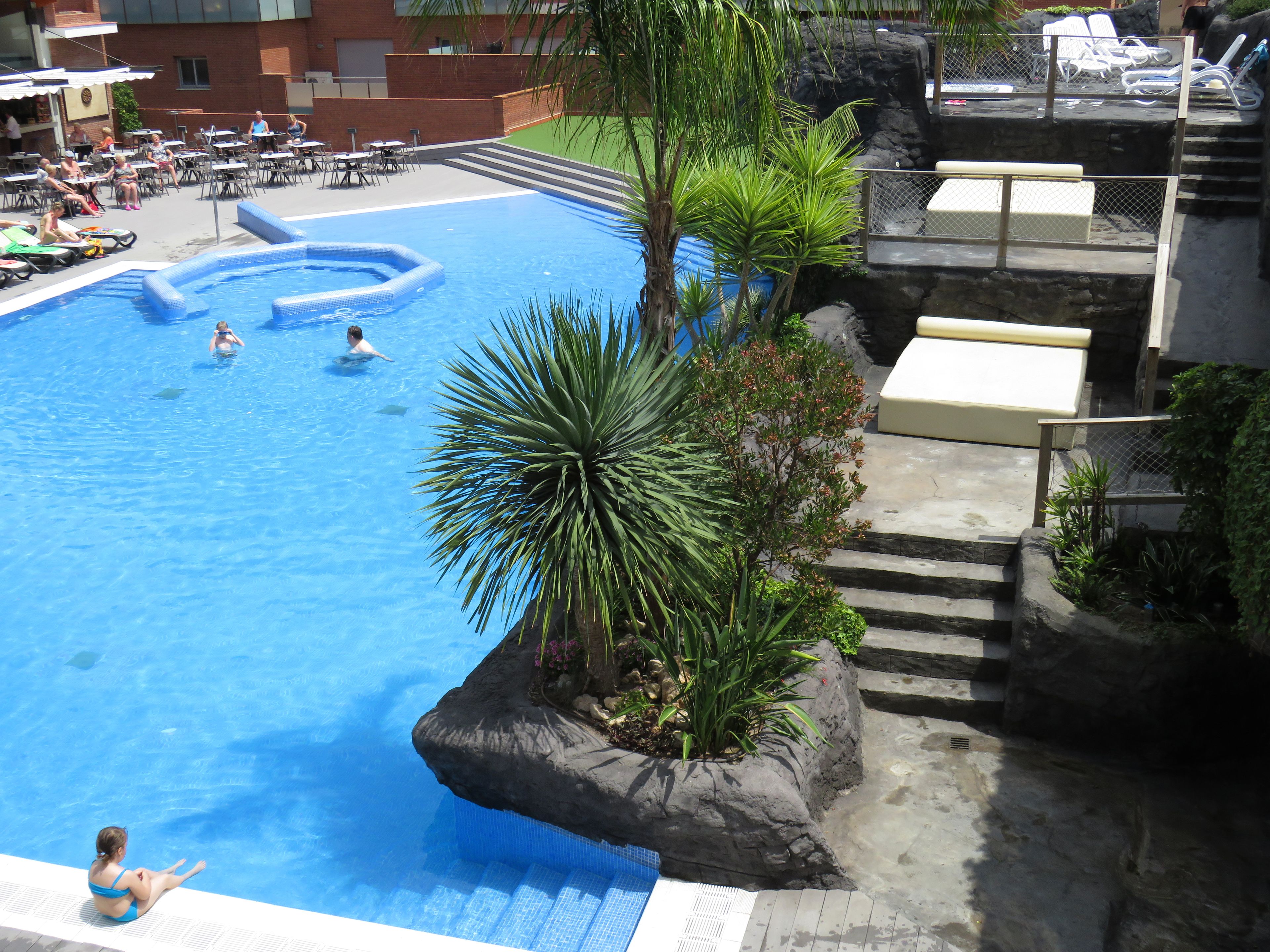 A swimming pool with a rock feature and lounge chairs.