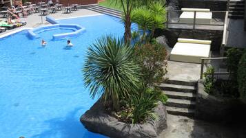A swimming pool with a rock feature and lounge chairs.