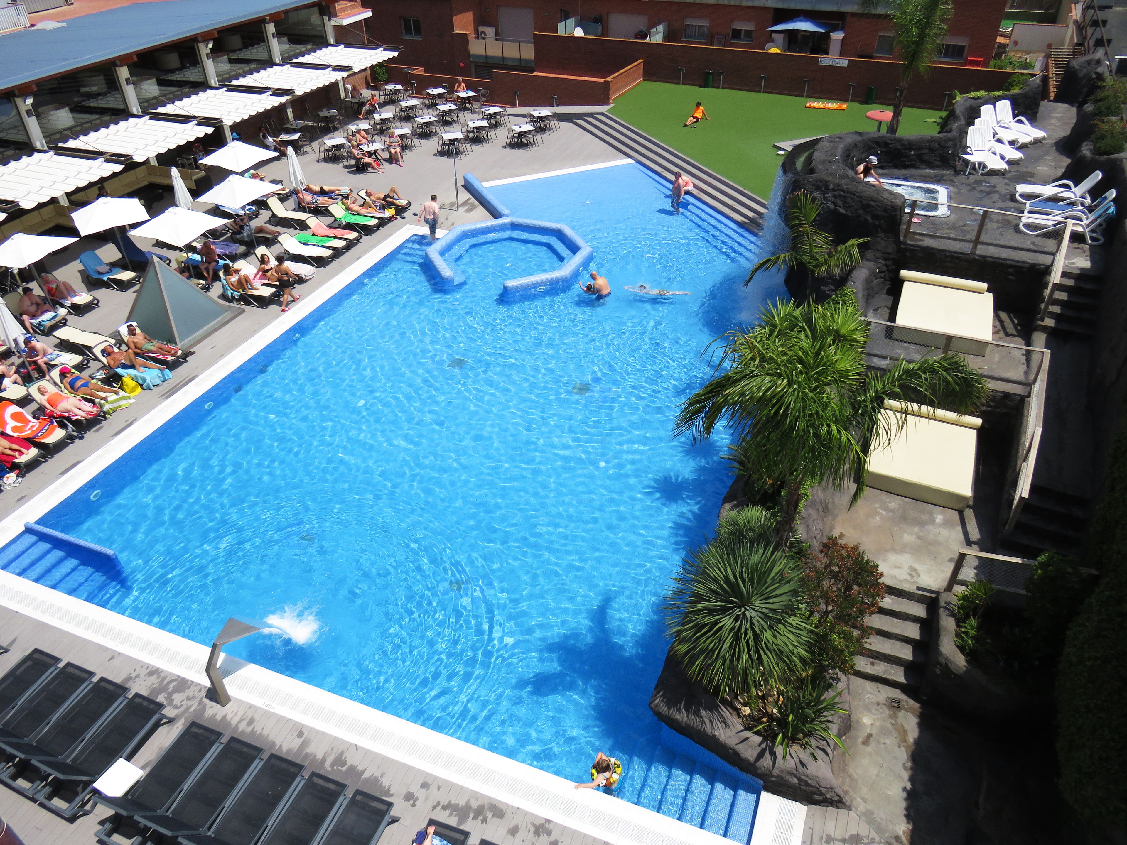 Une grande piscine intérieure dotée de plusieurs couloirs, entourée de chaises longues et de parasols.