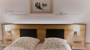 Een slaapkamer met een houten hoofdbord, twee bedlampen en bloemenbedrukte beddengoed.